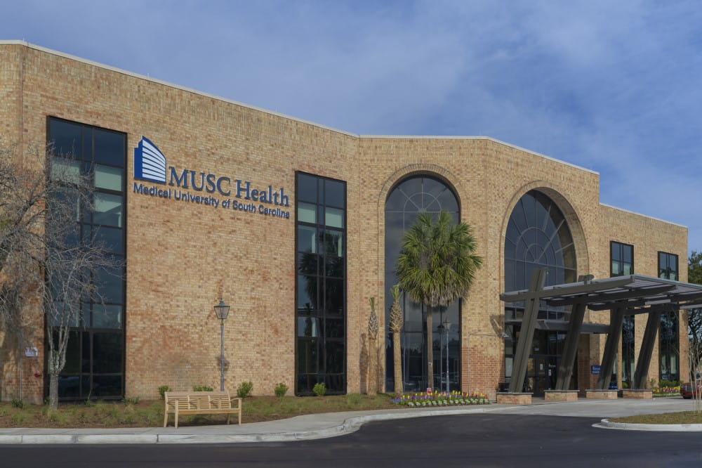 The exterior of the West Ashley Medical Pavilion, a two-story brick building with tall windows and the MUSC Health logo.