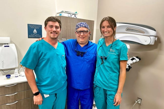 Dental students Craig Correa and Danielle Vines stand with  West Ashely Dental and Oral Health Center director, Dr. Al Natelli, in a patient room.