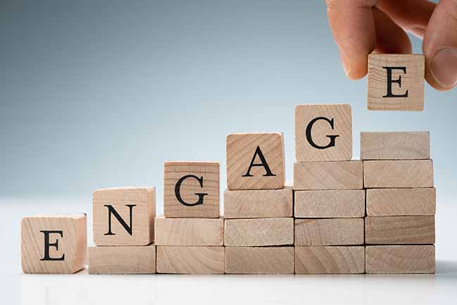 Person stacking blocks that spell the word "engage"